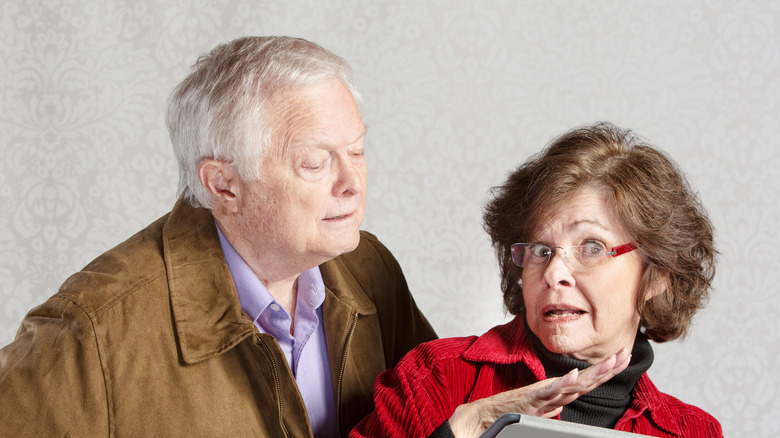 Older man peeking over shoulder of older woman