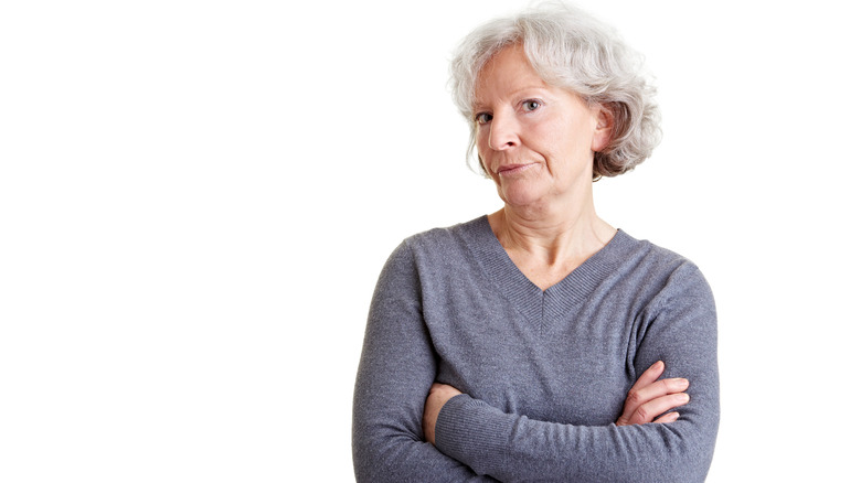 Older woman with crossed arms and judgmental expression