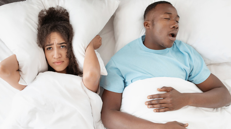 woman awake while man snores in bed