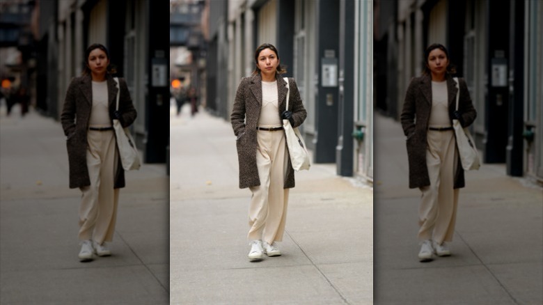 woman wearing cream outfit, coat, and white sneakers