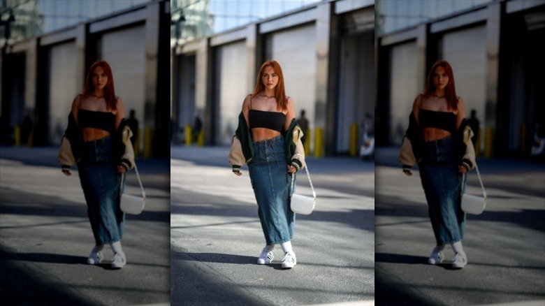 woman wearing crop top, denim skirt, and white sneakers