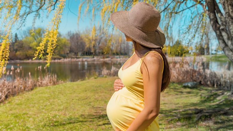 Pregnant model wearing sun hat in sunny weather