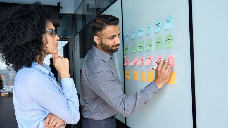 Two people writing on whiteboard