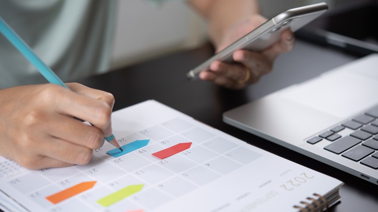 Person writing schedule in notebook