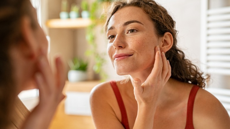 Woman looking in mirror at skin