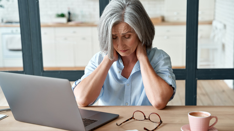 Stressed woman rubbing neck