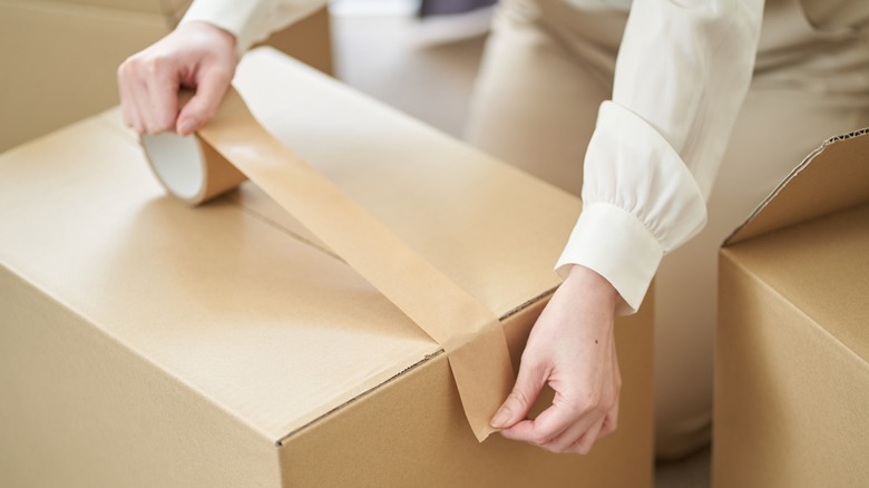 Person taping a cardboard moving box