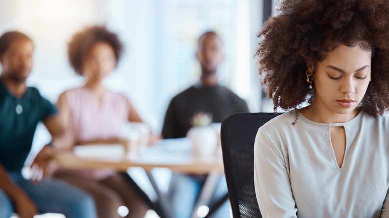 Woman sitting away from group of people