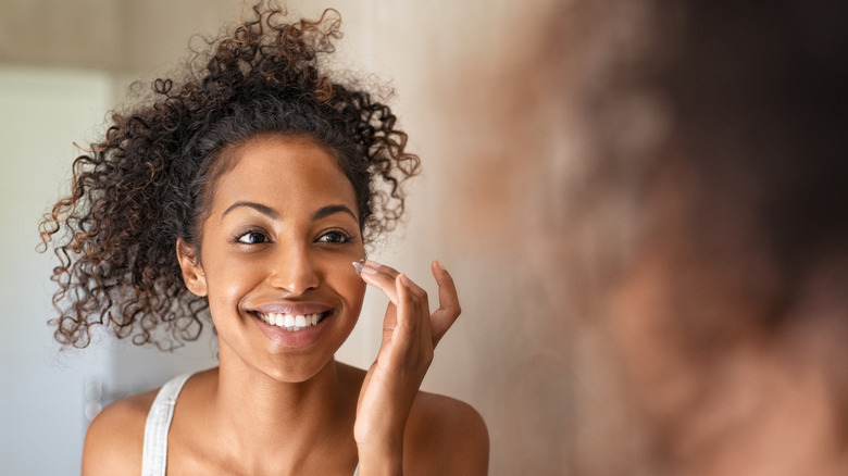 woman applying moisturizer to face