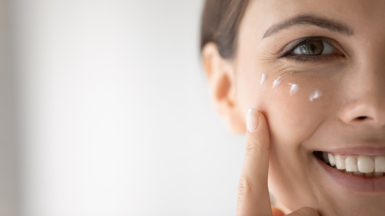 woman applying moisturizer under eyes