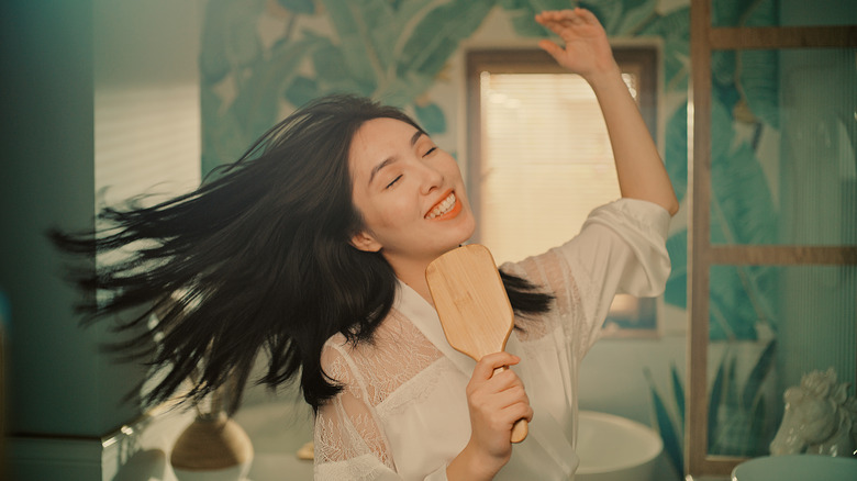 Happy woman using hairbrush