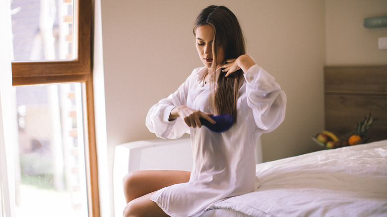 Woman brushing long brown hair with boar bristle brush