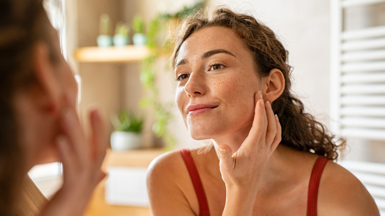 Woman looking at skin in a mirror