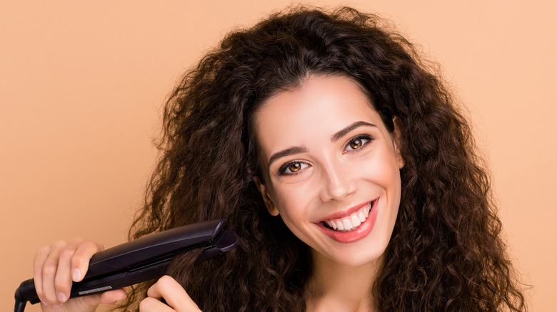 Model with curly hair using a flat iron