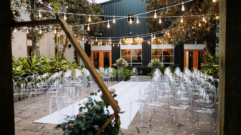 Outdoor wedding ceremony with clear chairs 