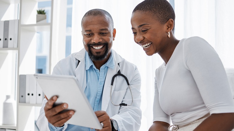 Woman looks at tablet with doctor