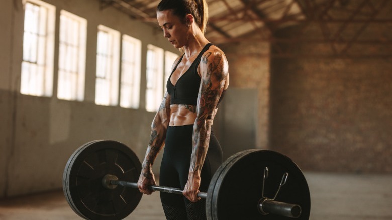 Tattooed woman deadlifting barbell