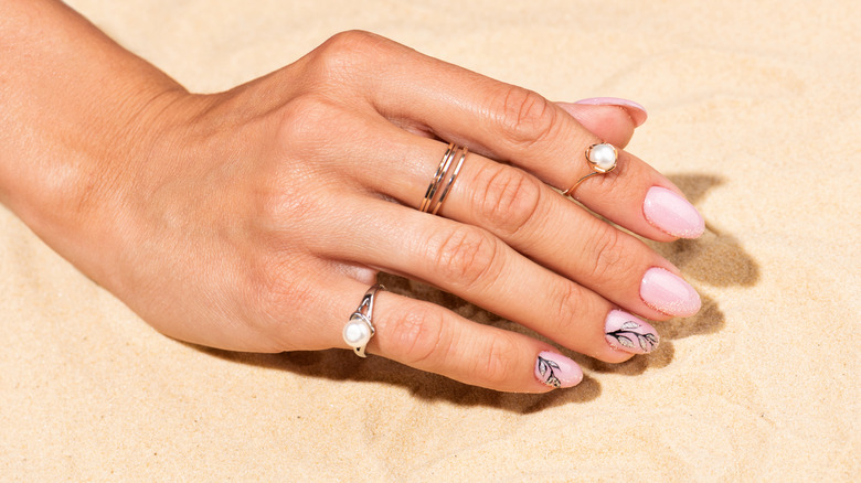 hand wearing rings in sand