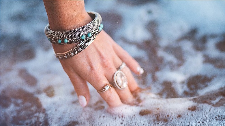 hand wearing jewelry in ocean