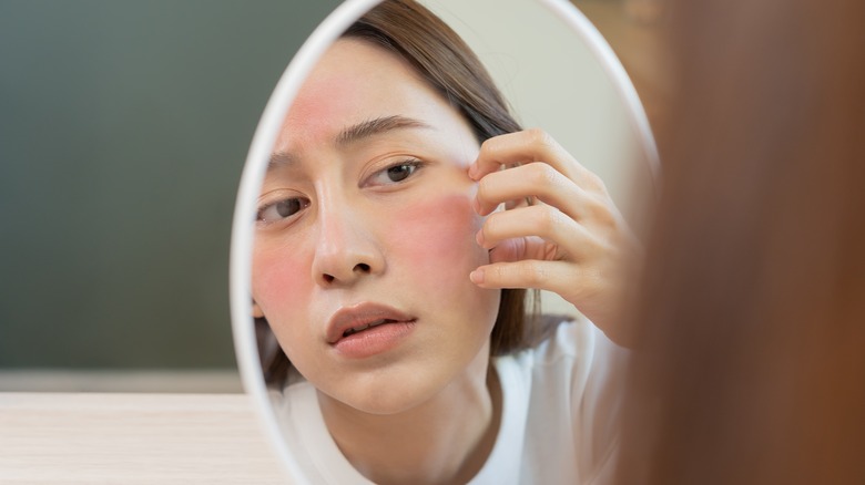 Girl studying skin in mirror.