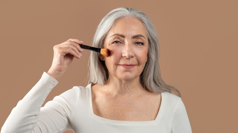 mature woman applying makeup