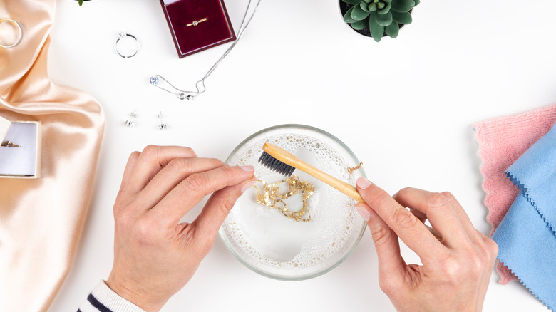 close up of person cleaning jewelry with a small brush 