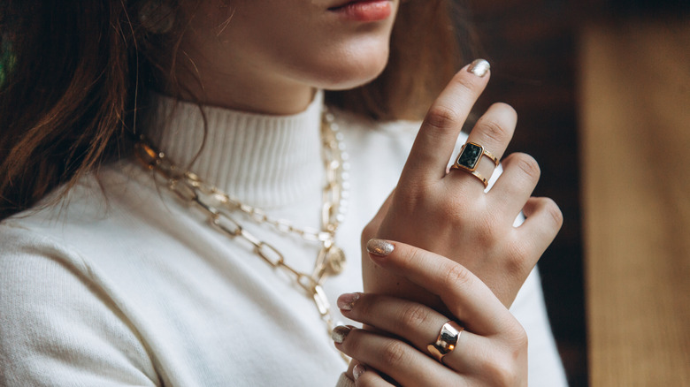 close up of woman wearing gold rings and necklaces