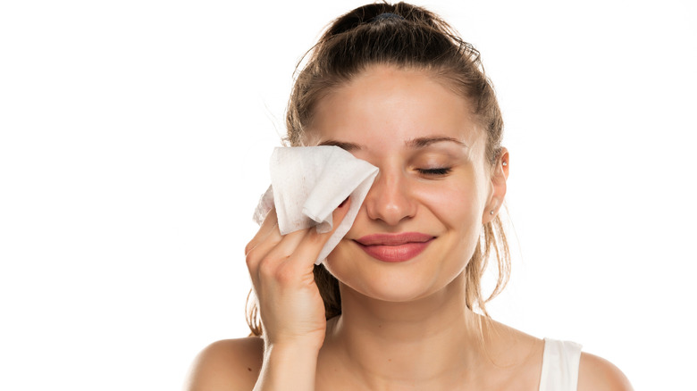 Smiling woman using makeup wipe