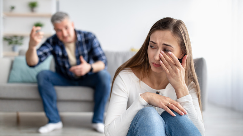 man raising hand woman crying