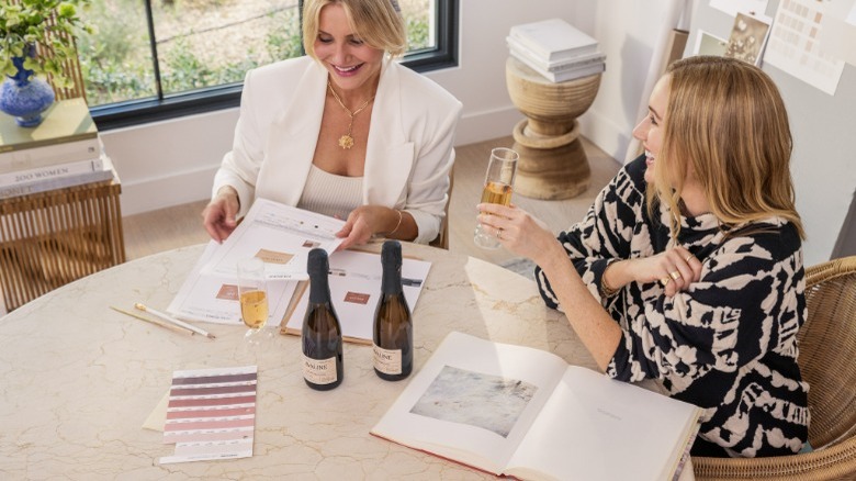 Two ladies with paperwork drinking Avaline wine
