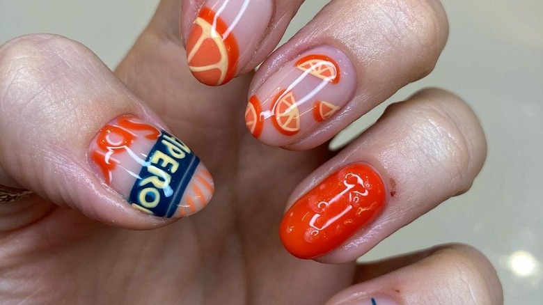 fingers with Aperol-themed art nails
