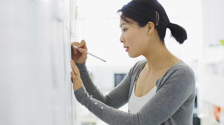 Woman writing on white board