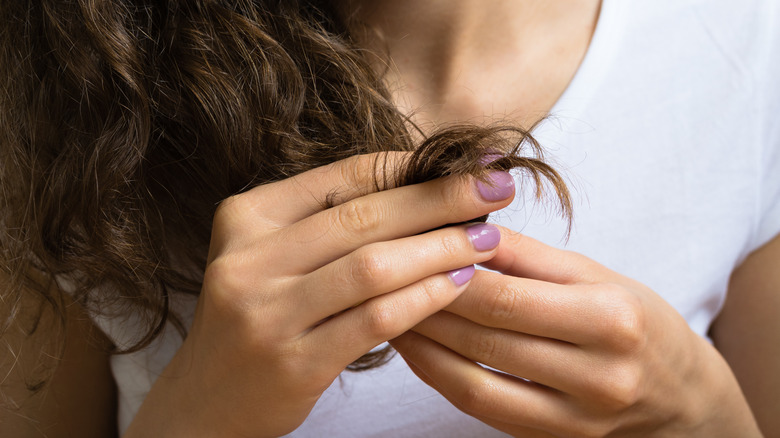 Woman looking at damaged hair.