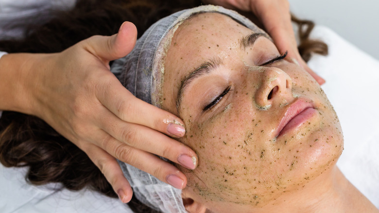 Woman receiving a facial with a green scrub