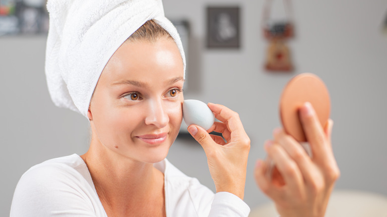 woman applying foundation to face