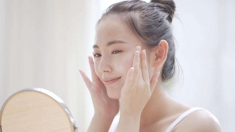 young woman applying moisturizer