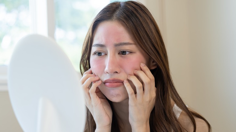 woman with irritated skin looking in mirror