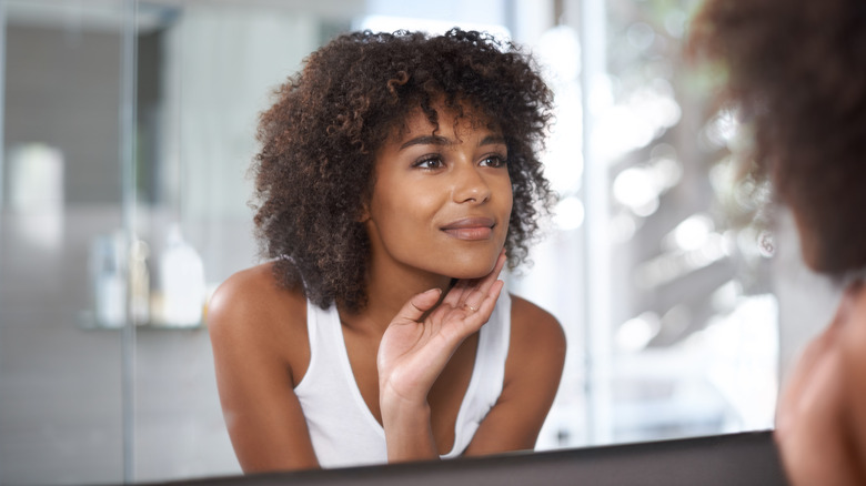 Woman looking in mirror, appearing pleased