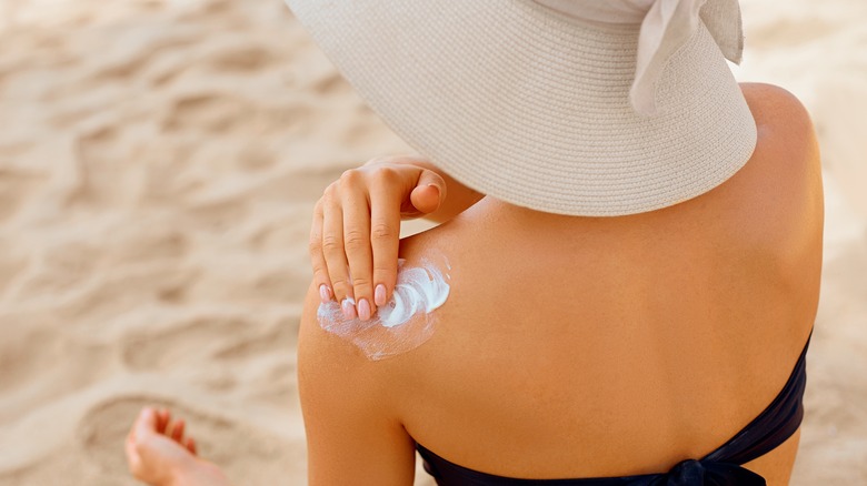 woman applies sunscreen on her shoulder