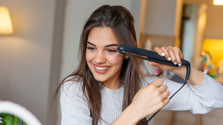 woman straightening her brown hair 