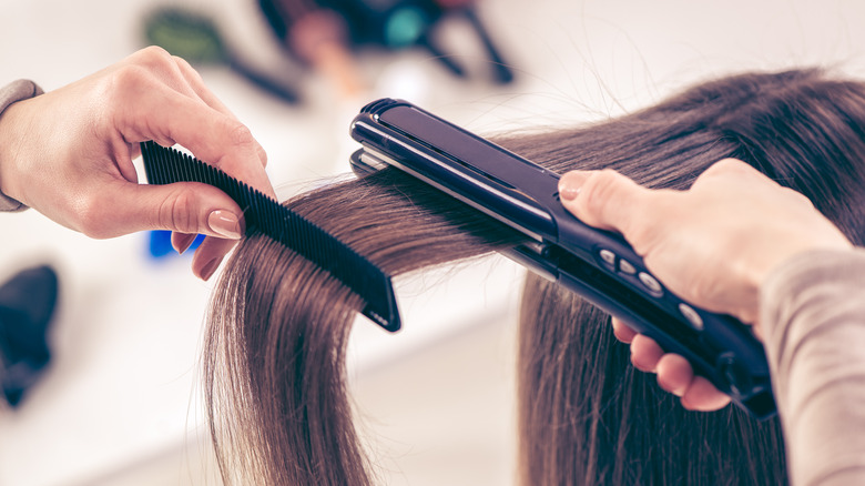 woman straightening another woman's hair 