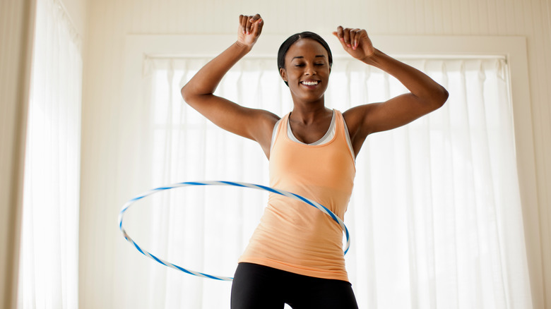 young woman hula hooping with fitness clothes on 