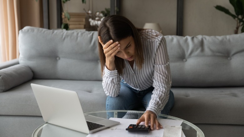 Stressed woman looking at calculator