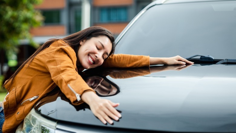 Woman hugging hood of car