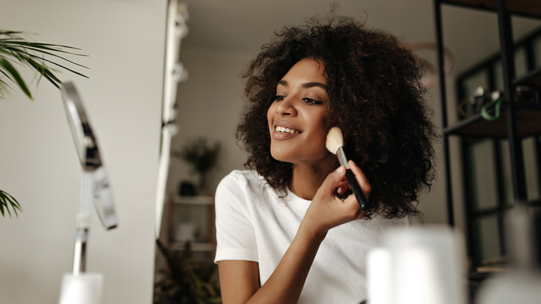 woman applying makeup with brush