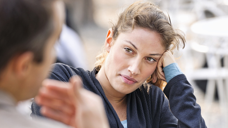 Skeptical woman watching man talk