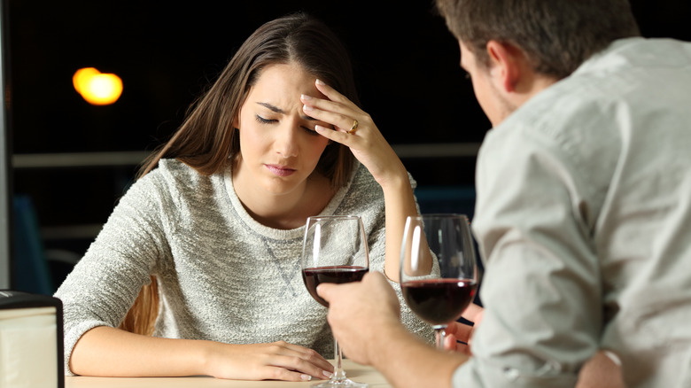 Unhappy woman at table with wine