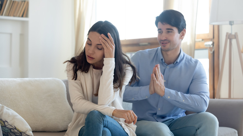 Woman ignoring husband on couch