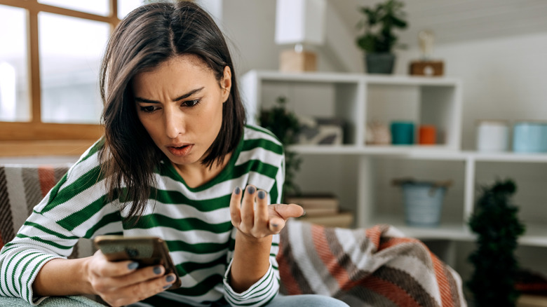 Confused woman looking at phone