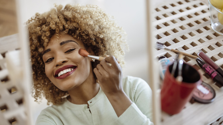 Woman applying blush to cheeks